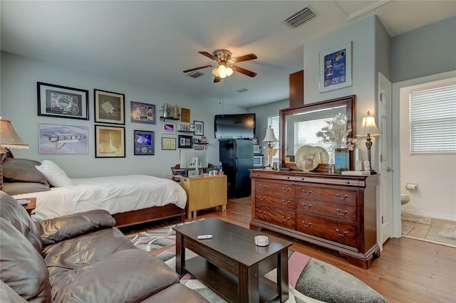 bedroom featuring ceiling fan, ensuite bathroom, multiple windows, and light hardwood / wood-style floors