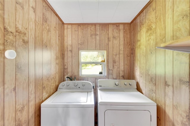 laundry area featuring crown molding, separate washer and dryer, and wooden walls