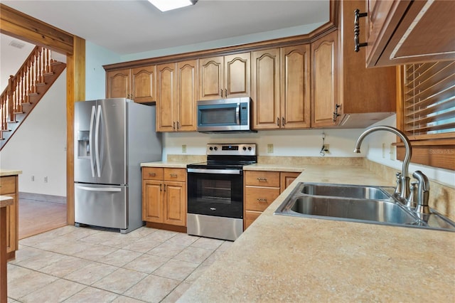 kitchen featuring stainless steel appliances, light tile patterned floors, and sink