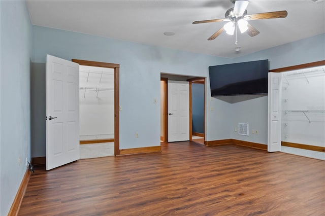 unfurnished bedroom with ceiling fan, a closet, dark hardwood / wood-style floors, and a spacious closet