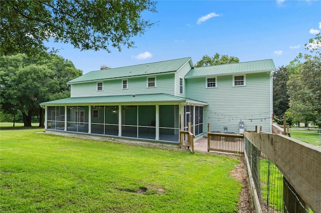 rear view of house with a sunroom and a lawn