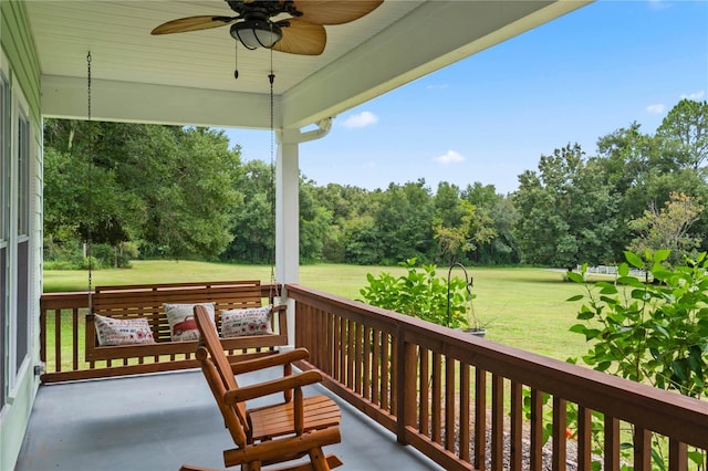 wooden terrace with ceiling fan and a yard