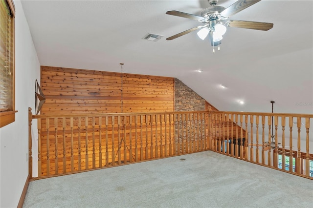 additional living space featuring ceiling fan, carpet floors, lofted ceiling, and wood walls