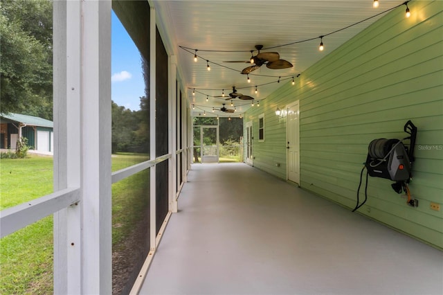 unfurnished sunroom with rail lighting and ceiling fan