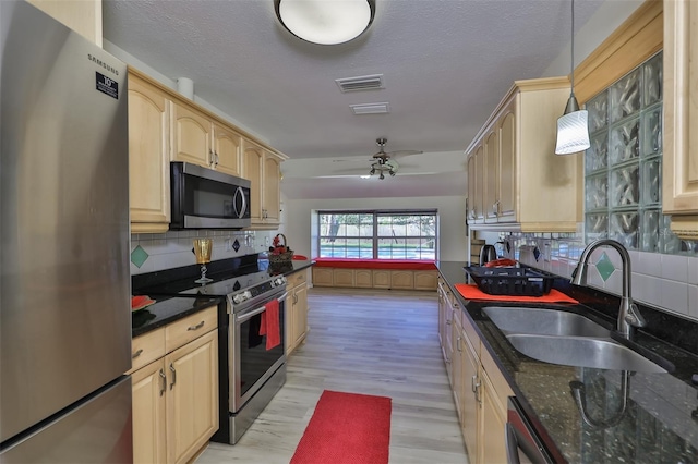 kitchen featuring pendant lighting, tasteful backsplash, stainless steel appliances, sink, and ceiling fan