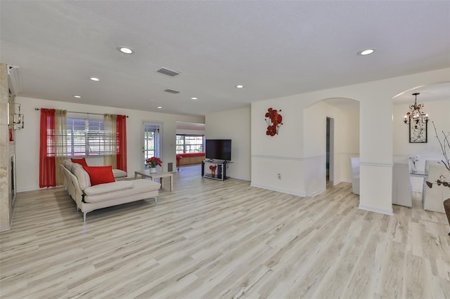 living room featuring a textured ceiling, light hardwood / wood-style flooring, and an inviting chandelier