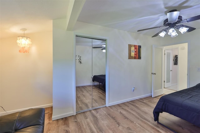 bedroom with a closet, ceiling fan with notable chandelier, and light hardwood / wood-style floors