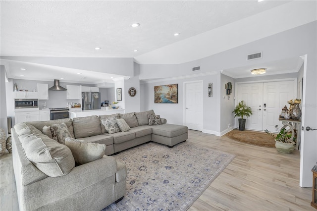 living room with ornamental molding, vaulted ceiling, and light hardwood / wood-style flooring