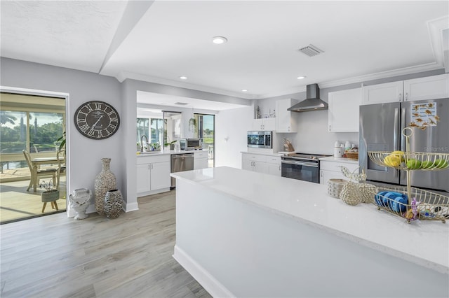 kitchen featuring white cabinetry, light hardwood / wood-style flooring, sink, wall chimney exhaust hood, and appliances with stainless steel finishes