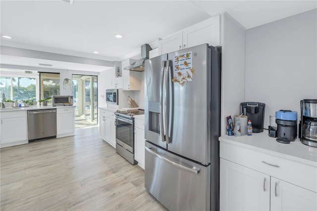 kitchen featuring white cabinets, appliances with stainless steel finishes, light hardwood / wood-style floors, sink, and wall chimney exhaust hood