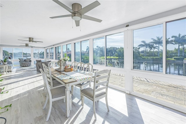 sunroom / solarium with a water view and ceiling fan