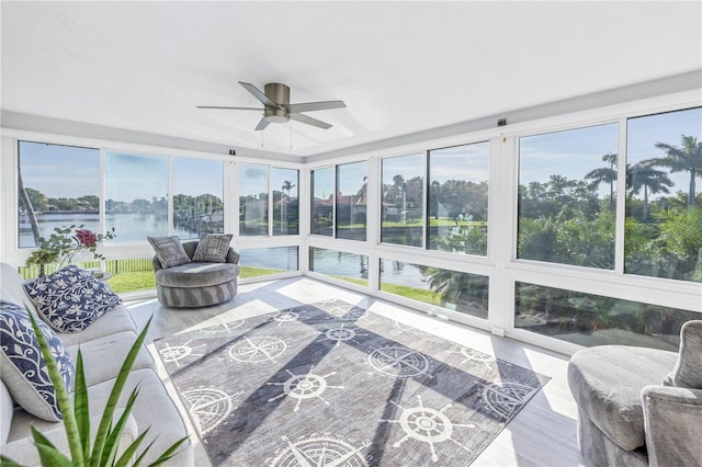 sunroom featuring a water view and ceiling fan