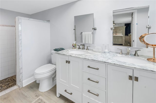 bathroom with tiled shower, toilet, hardwood / wood-style flooring, and vanity