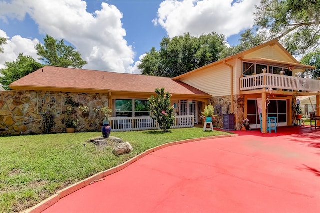 rear view of house featuring a balcony and a yard