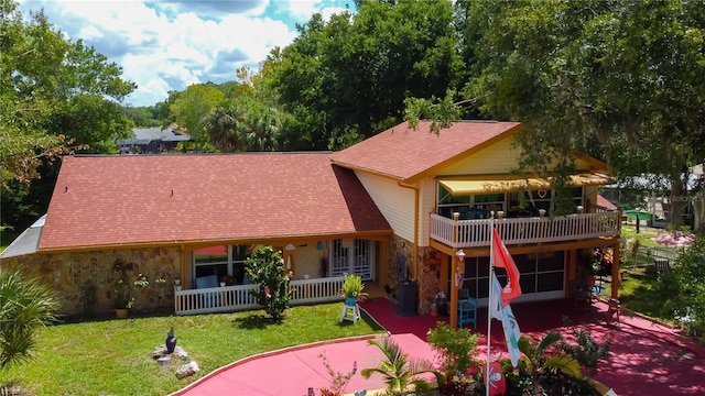 back of house with a balcony, a yard, and covered porch