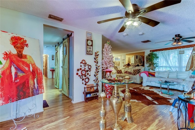 living room with hardwood / wood-style floors, ceiling fan, and a textured ceiling