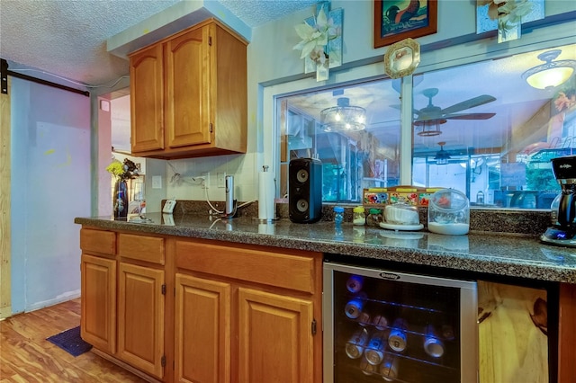 kitchen with a barn door, a textured ceiling, wine cooler, and light hardwood / wood-style flooring