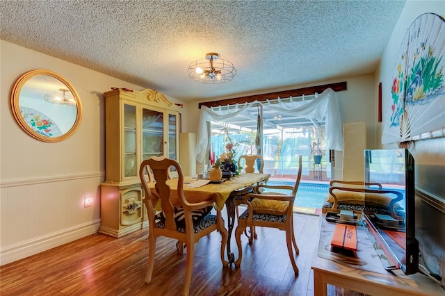 dining space with hardwood / wood-style flooring and a textured ceiling