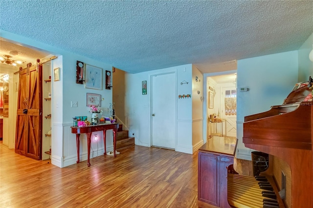 miscellaneous room with a textured ceiling, a barn door, and wood-type flooring