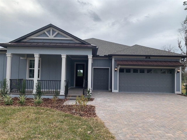 view of front of home with a porch, a front yard, and a garage