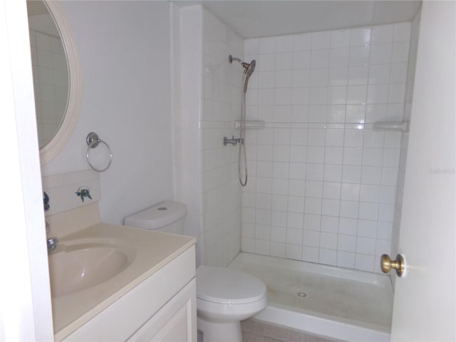 bathroom with tiled shower, toilet, and vanity