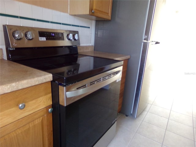 kitchen with backsplash, electric stove, and light tile patterned flooring