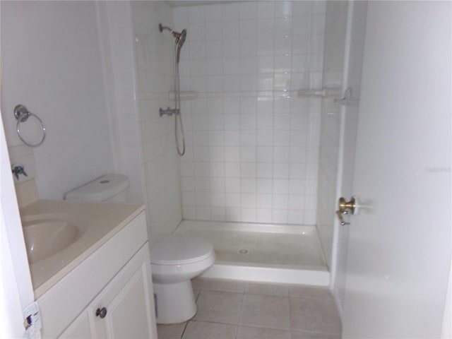 bathroom featuring tiled shower, tile patterned flooring, toilet, and vanity