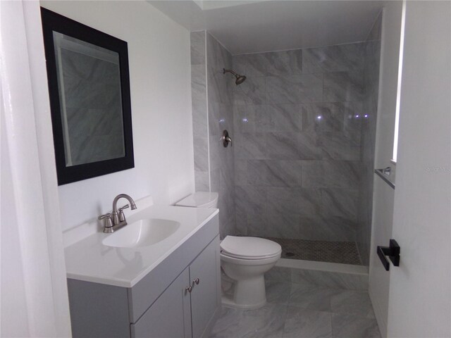 bathroom with tiled shower, toilet, and vanity