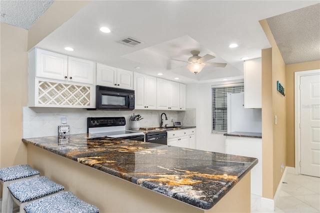 kitchen featuring black appliances, dark stone countertops, decorative backsplash, and white cabinetry