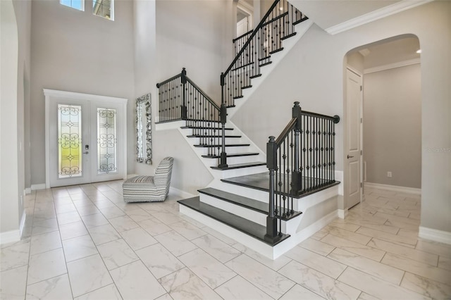 stairway featuring a towering ceiling and ornamental molding