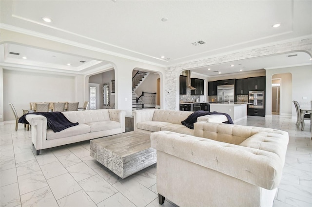 living room with crown molding, a tray ceiling, and sink