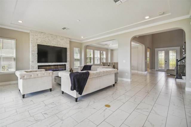 living room with ornamental molding, a wealth of natural light, and a stone fireplace