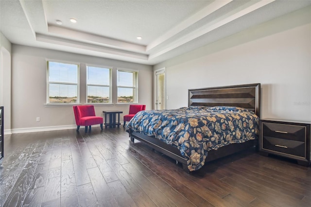 bedroom with dark wood-type flooring and a raised ceiling