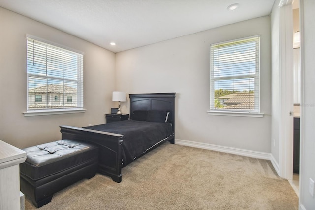 bedroom featuring light colored carpet and multiple windows