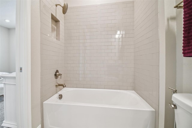 bathroom with toilet and tiled shower / bath