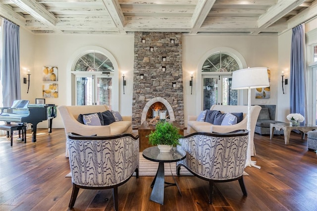 living area featuring dark hardwood / wood-style flooring, a wealth of natural light, beam ceiling, and a stone fireplace