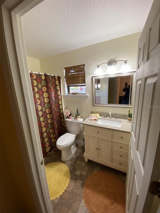 bathroom with a textured ceiling, vanity, and toilet