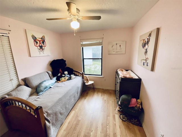 bedroom with light wood-type flooring, a textured ceiling, and ceiling fan