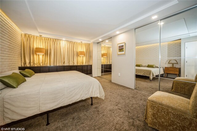 carpeted bedroom featuring brick wall and a closet