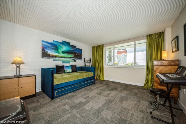 bedroom featuring brick wall and dark carpet