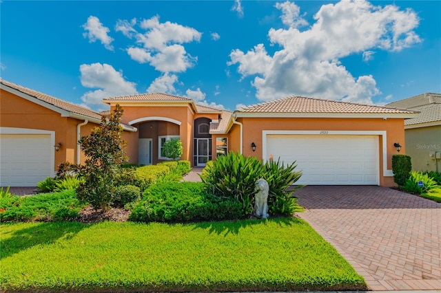 mediterranean / spanish home with a garage and a front lawn