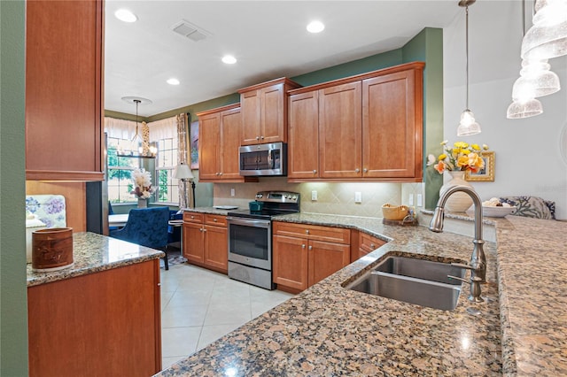 kitchen featuring stone counters, light tile patterned floors, stainless steel appliances, sink, and hanging light fixtures