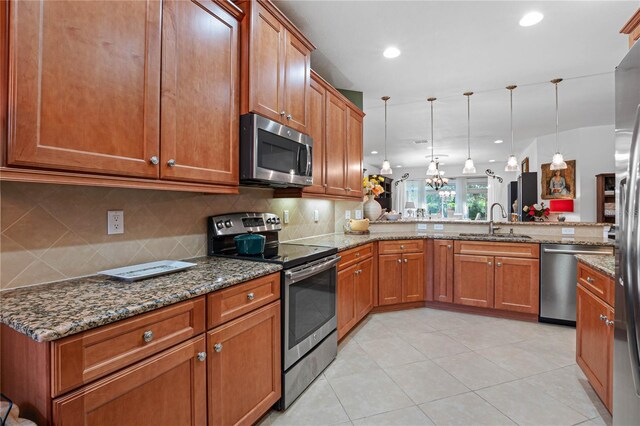 kitchen with pendant lighting, kitchen peninsula, sink, and appliances with stainless steel finishes