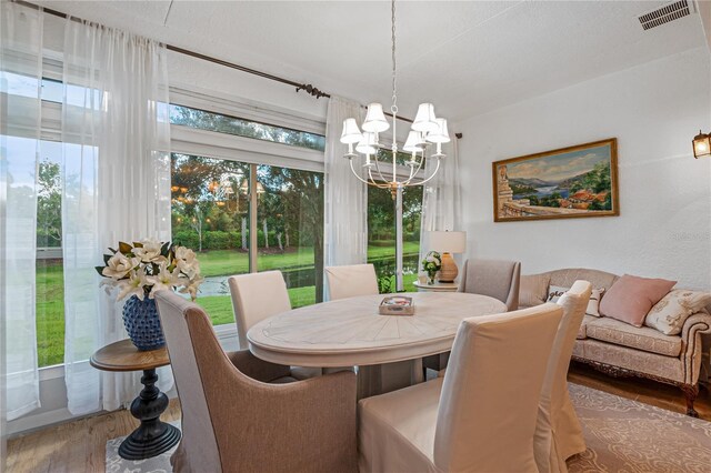 dining space with a textured ceiling, dark hardwood / wood-style floors, and a chandelier