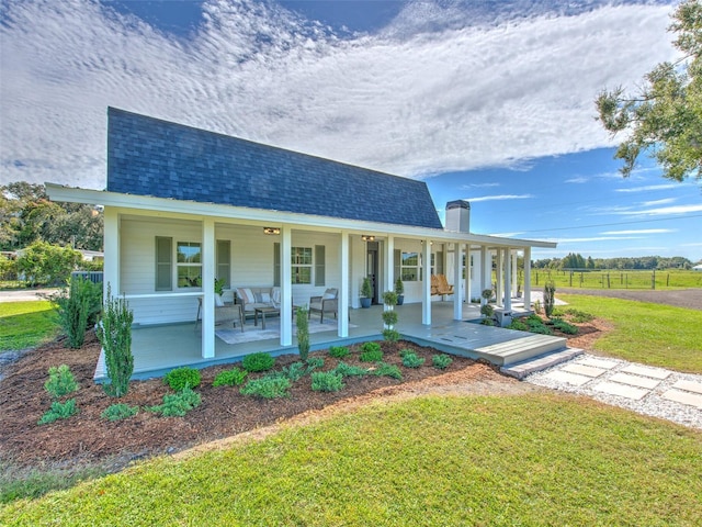 farmhouse inspired home featuring a front lawn, a porch, and an outdoor hangout area