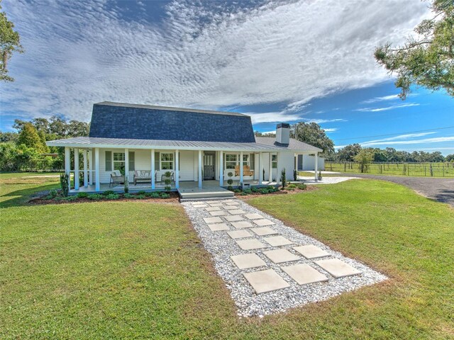 view of front of property with a front yard, a porch, fence, and a chimney