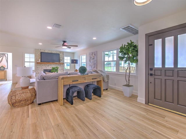 living room with a fireplace, light hardwood / wood-style flooring, and ceiling fan