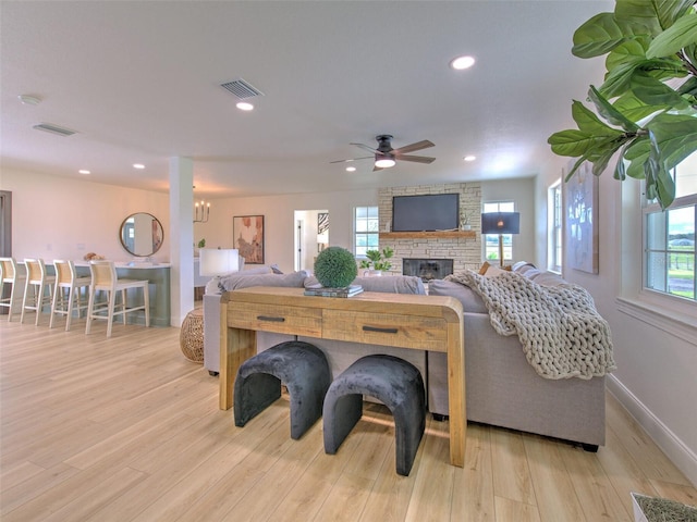 living room with a fireplace, light wood-type flooring, plenty of natural light, and ceiling fan