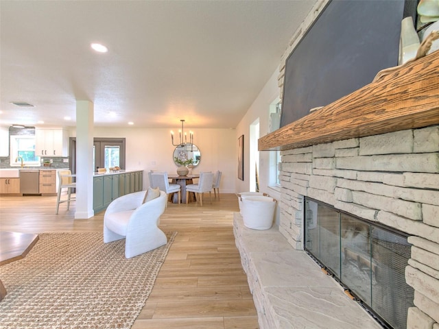 living room with light hardwood / wood-style flooring and a stone fireplace