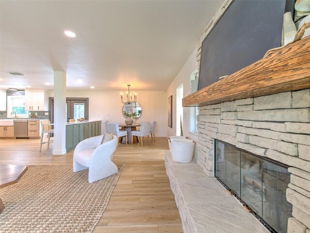 unfurnished living room featuring light wood finished floors, baseboards, a fireplace, recessed lighting, and a notable chandelier